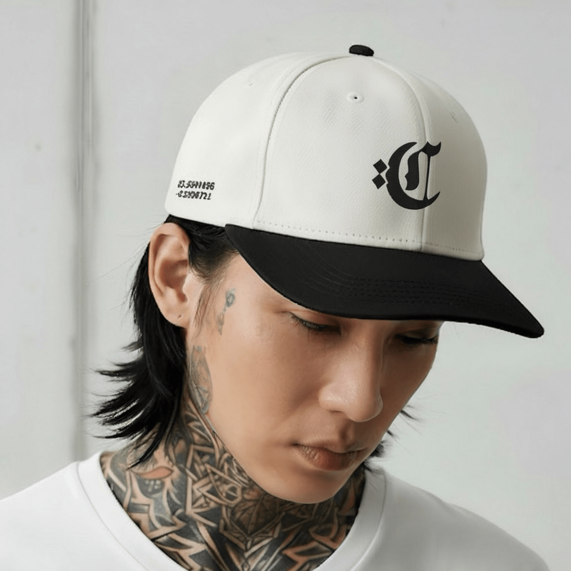 Person wearing a white and black cap with a logo, looking down.