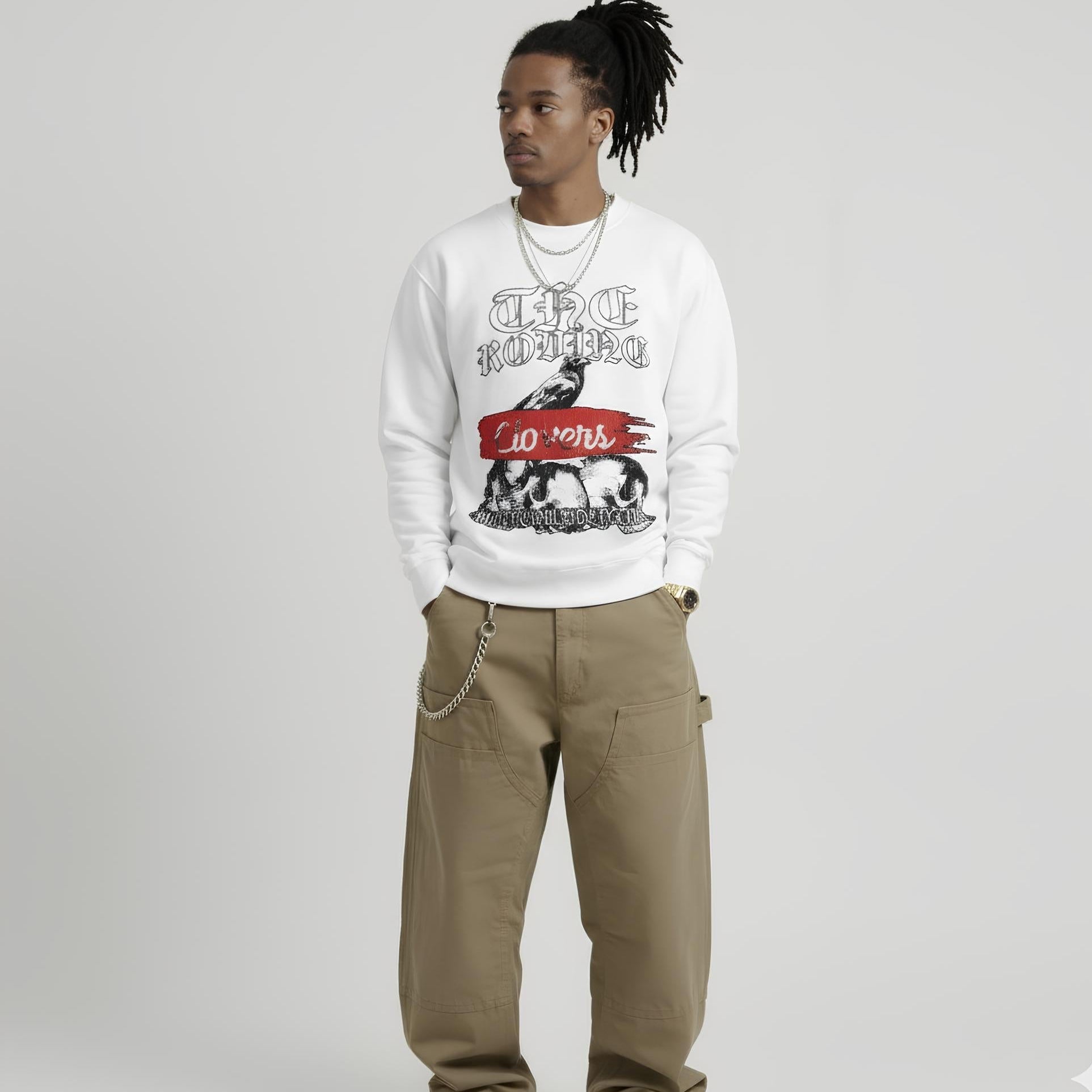 Person wearing a white sweatshirt with graphic design and beige pants on a light gray background