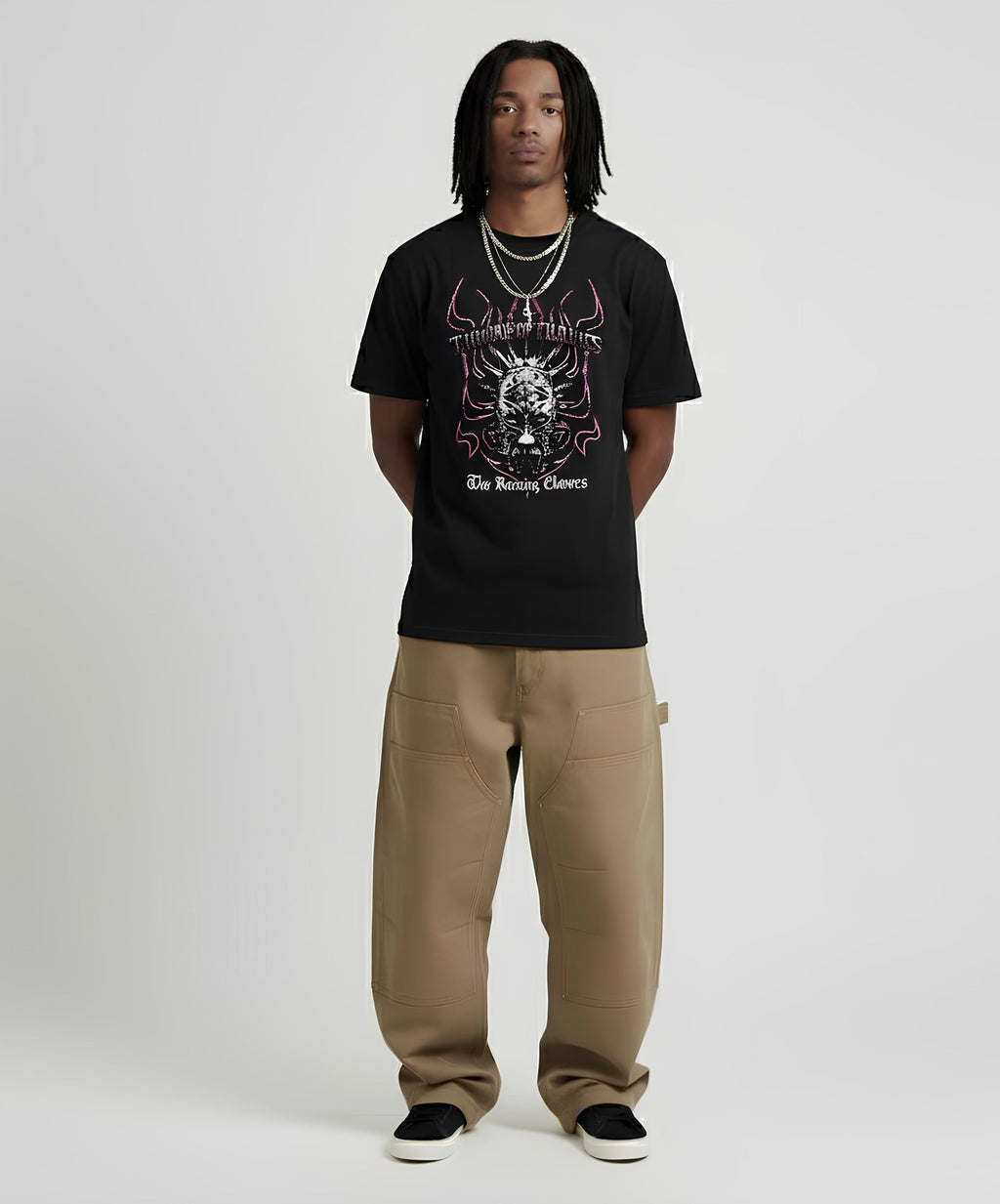 Person wearing a black t-shirt with graphic design and beige pants on a white background
