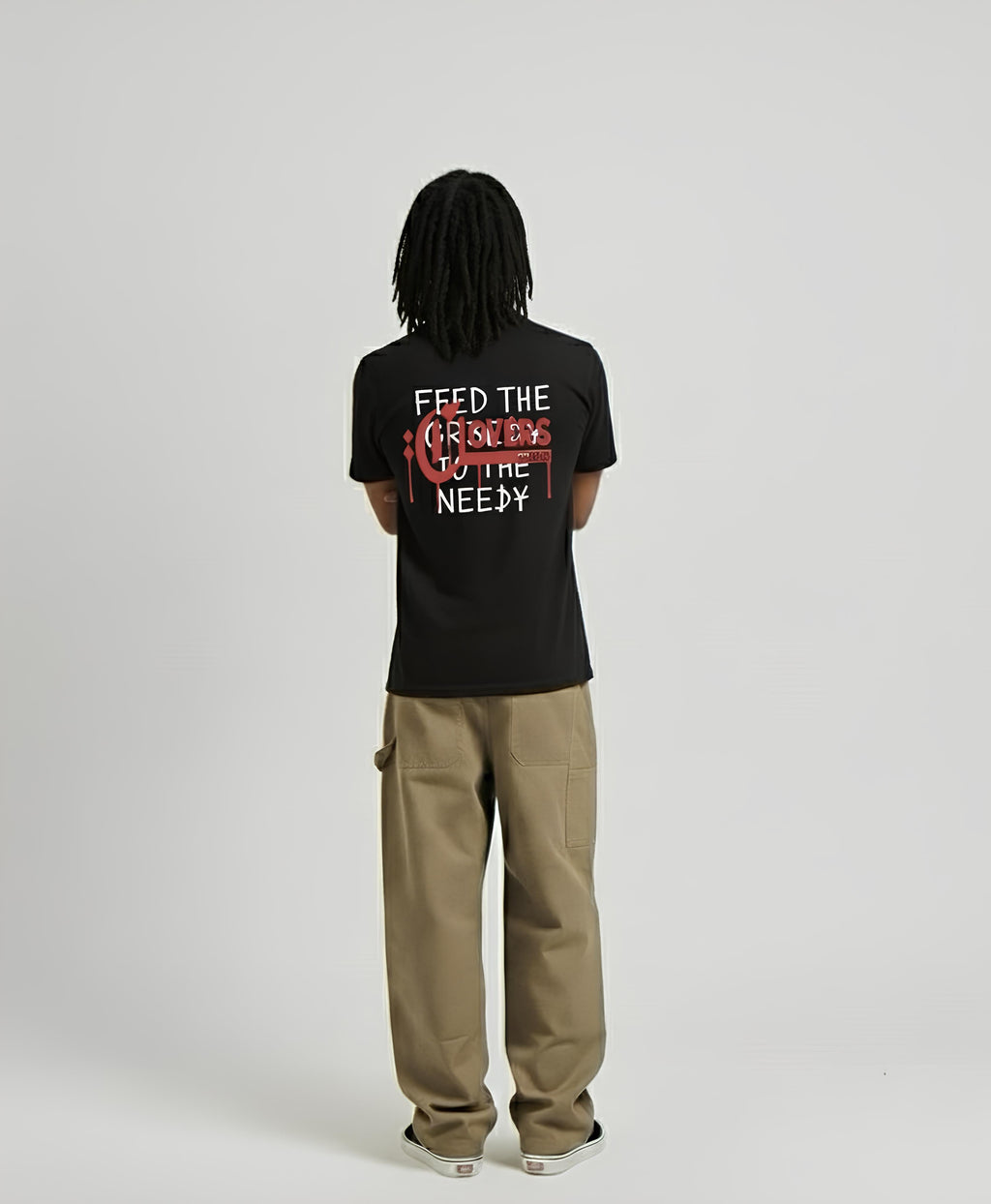 Person wearing a black t-shirt with text on the back, standing against a plain background