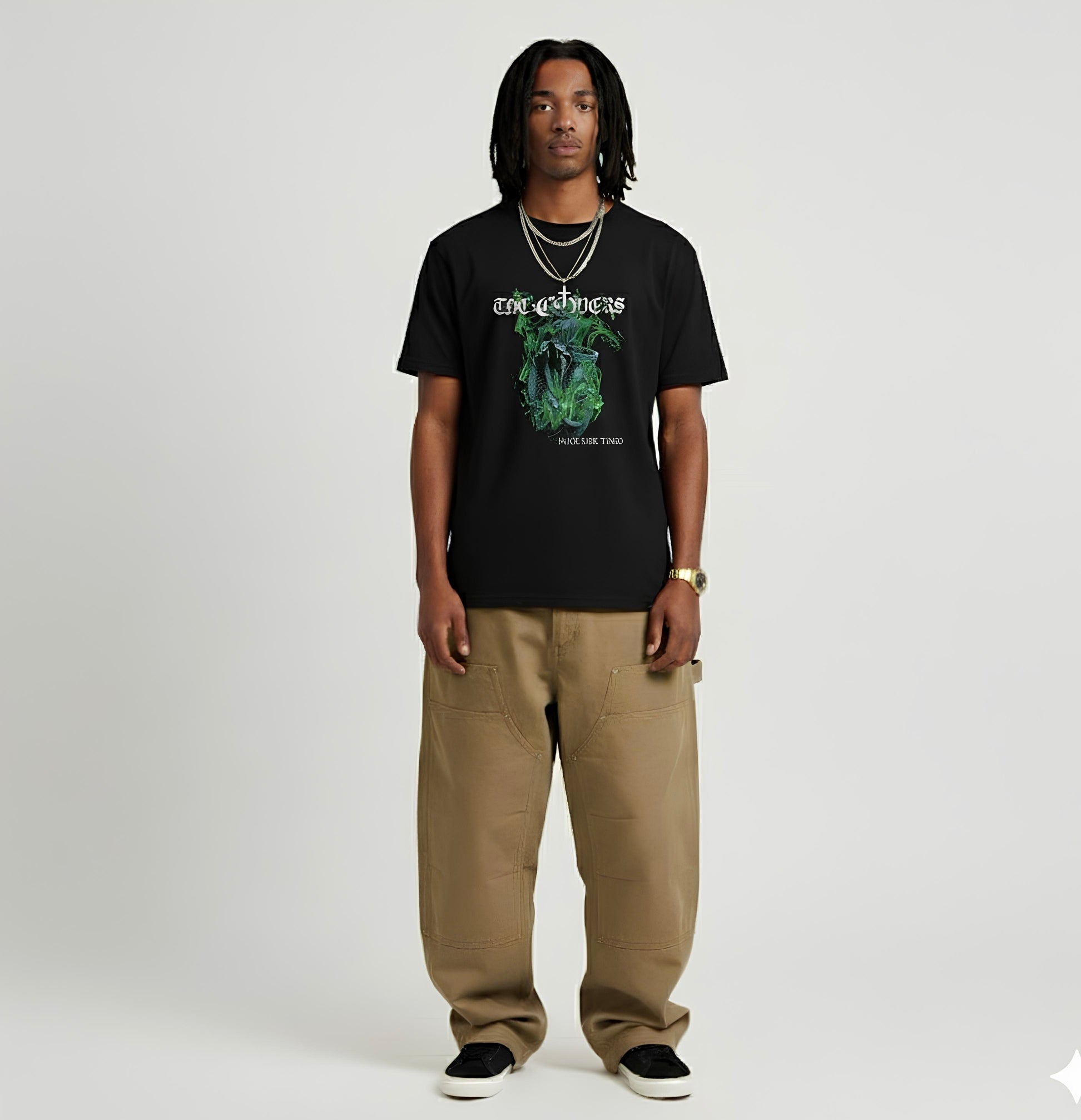 Person wearing a black t-shirt with a graphic design and beige pants on a white background